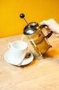 Female Hands Pour Tea from Brewer into Mug on Wooden Table