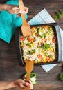 Female hands poured baked pasta with broccoli and cheesy tomato sauce on wood background Royalty Free Stock Photo