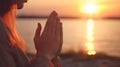 Female hands praying at beach at sunset Royalty Free Stock Photo