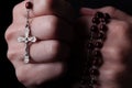 Female hands praying holding a rosary with Jesus Christ in the cross or Crucifix on black background. Royalty Free Stock Photo