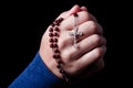 Female hands praying holding a rosary with Jesus Christ in the cross or Crucifix on black background. Royalty Free Stock Photo