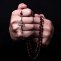 Female hands praying holding a rosary with Jesus Christ in the cross or Crucifix on black background. Royalty Free Stock Photo