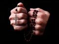 Female hands praying holding a rosary with Jesus Christ in the cross or Crucifix on black background Royalty Free Stock Photo