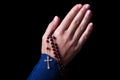 Female hands praying holding a rosary with Jesus Christ in the cross or Crucifix on black background. Royalty Free Stock Photo