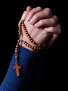 Female hands praying holding a rosary with Jesus Christ in the cross or Crucifix on black background. Royalty Free Stock Photo