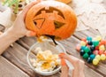 Female hands preparing jack-o-lantern pumpkin for Halloween.