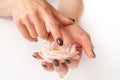 Female hands with purple nails color and tinsel touching pink rose flower on white background Royalty Free Stock Photo