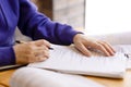 Female hands in purple sweater holding papers and signing them. Royalty Free Stock Photo