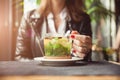 Female hands with red manicure holding cup of tea with herbs and lemon on table in cafe. Royalty Free Stock Photo