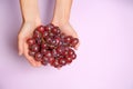 Female hands with ripe tasty grapes on color background