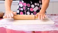 Female hands roll out the dough with a rolling pin on a wooden surface, close-up. female hands rolling dough on a lilac Royalty Free Stock Photo