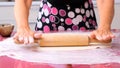 Female hands roll out the dough with a rolling pin on a wooden surface, close-up. female hands rolling dough on a lilac Royalty Free Stock Photo