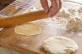 Female hands roll out the dough with a wooden rolling pin on a board with flour. Royalty Free Stock Photo