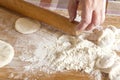 Female hands roll out the dough with a wooden rolling pin on a board with flour. Royalty Free Stock Photo