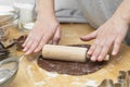 Female hands rolling chocolate dough with rolling-pin. Cooking homemade cookies or pastry, dessert Royalty Free Stock Photo