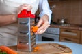 Female hands are rubbing fresh orange carrots on a steel silver grater. Grated carrots. Woman Chef prepares ingredients for
