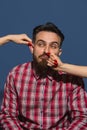 Female hands rumple young bearded handsome man on blue background