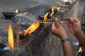Female hands set fire to fragrant sticks in the temple offerings