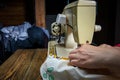 Female hands sew a blue dress on a professional overlock machine in a workshop. Seamstress hands holding textile for Royalty Free Stock Photo