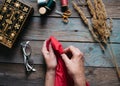 Female hands sewing on wooden table, scissors, casket, thread, glasses