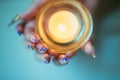 Female hands with sharp nails holding a candlestick with a burning candle Royalty Free Stock Photo