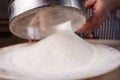 Female hands sifting flour from old sieve on old wooden kitchen table. Vintage kitchenware with flour, water and eggs at Royalty Free Stock Photo