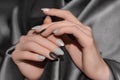 Female hands with silver nail design. Glitter black nail polish manicure. Woman hands on gray fabric background Royalty Free Stock Photo