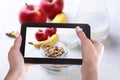 Female hands with a smartphone, on the screen of which is a photo of Healthy food with corn flakes cereal in a bowl Royalty Free Stock Photo