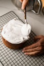 Female hands spread icing on an Easter cake with a spoon Royalty Free Stock Photo