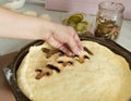 Female hands spread out the mushrooms on the pizza, homemade meal