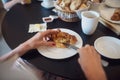 Female hands spreading butter and jam on delicious croissant