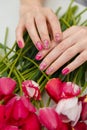 Female hands with spring manicure and tulips nail art, floral design on flowers background. Beauty, fingernails and hands care Royalty Free Stock Photo