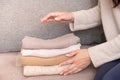 Female hands stack cozy knitted sweaters on the sofa. Warm concept