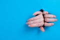 Female hands sticking out through a hole on a blue background.