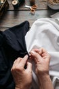 Female hands stitches black and white fabric on wooden table, scissors, casket, thread, glasses Royalty Free Stock Photo