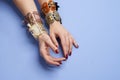 Female hands with stylish bracelets on a blue background with copy space