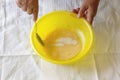 Female hands sugar with a raw egg in a yellow bowl, on a white towel background. Step by step cooking of pancakes. Step 3. Close- Royalty Free Stock Photo