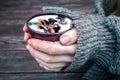 Woman holds hot cup of coffee mocha with white foam and chocolate, warming your hands in warm knitted sweater on wooden background Royalty Free Stock Photo