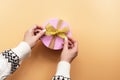 Female hands in a sweater wrapping a present. Women`s hands untie the bow on the gift box. Festive background, valentines day.