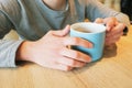 Female hands at table hold ceramic mug with black coffee. The concept of coffee break