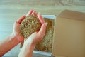 Female hands take grass seeds from a cardboard shipping box. Preparing for sowing a lawn Royalty Free Stock Photo