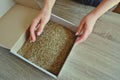 Female hands take grass seeds from a cardboard shipping box. Preparing for sowing a lawn