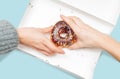 Female hands is taking last donuts in box on pastel blue background