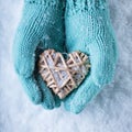 Female hands in teal knitted mittens with a entwined vintage romantic heart on a snow background. Love and St. Valentine concept Royalty Free Stock Photo