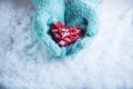 Female hands in teal knitted mittens with a entwined vintage romantic heart on a snow background. Love and St. Valentine concept Royalty Free Stock Photo