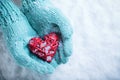 Female hands in teal knitted mittens with a entwined vintage romantic heart on a snow background. Love and St. Valentine concept Royalty Free Stock Photo