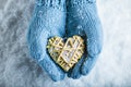 Female hands in teal knitted mittens with a entwined vintage romantic heart on a snow background. Love and St. Valentine concept