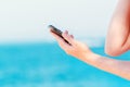 Female hands texting message on mobile phone on seaside Royalty Free Stock Photo