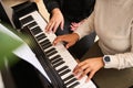 Female hands touching white and black piano keys while performing a musical composition, playing grand piano indoor