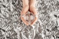 Female hands with trendy silver nail design on foil background holding silver Christmas ball. Festive backdrop for Royalty Free Stock Photo